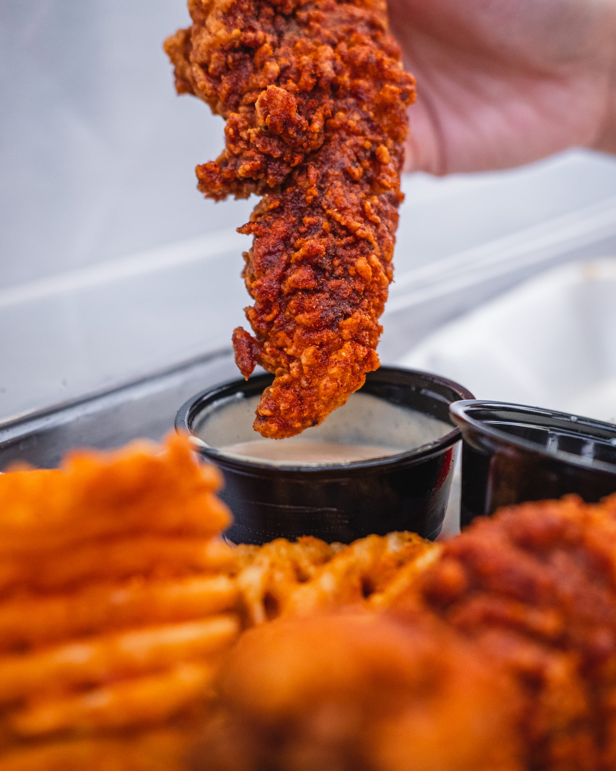 Our hot chicken tender, Waffle fries and our signature yummy's sauce